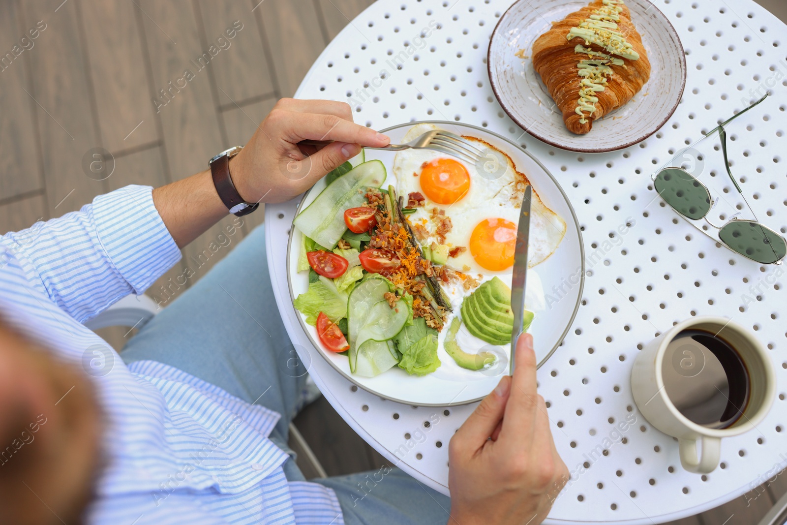 Photo of Man having tasty breakfast in outdoor cafe, top view