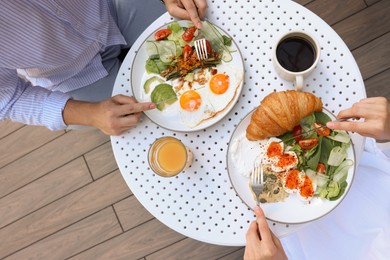 Photo of Couple having tasty breakfast in outdoor cafe, top view