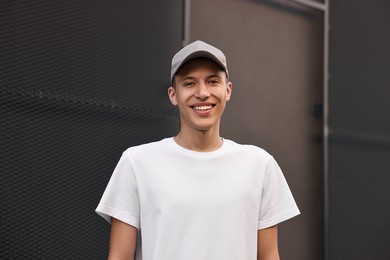 Portrait of smiling man in baseball cap near dark wall