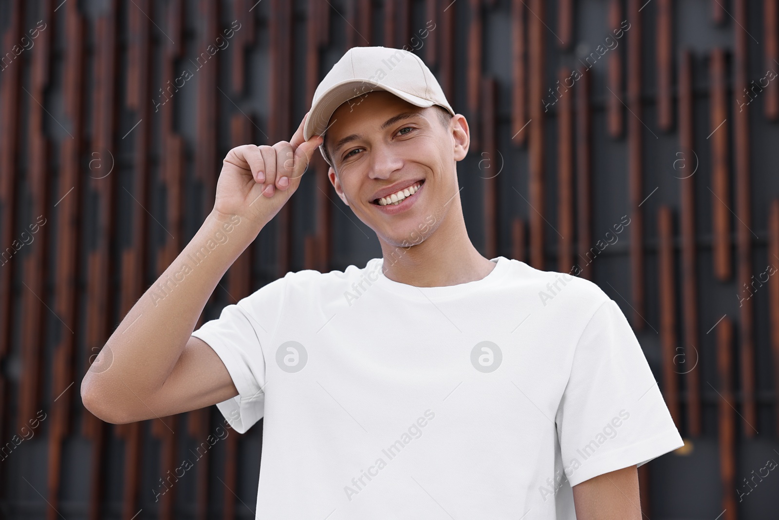 Photo of Portrait of smiling man in baseball cap near dark wall