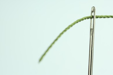 Photo of Sewing needle with green thread on white background, closeup