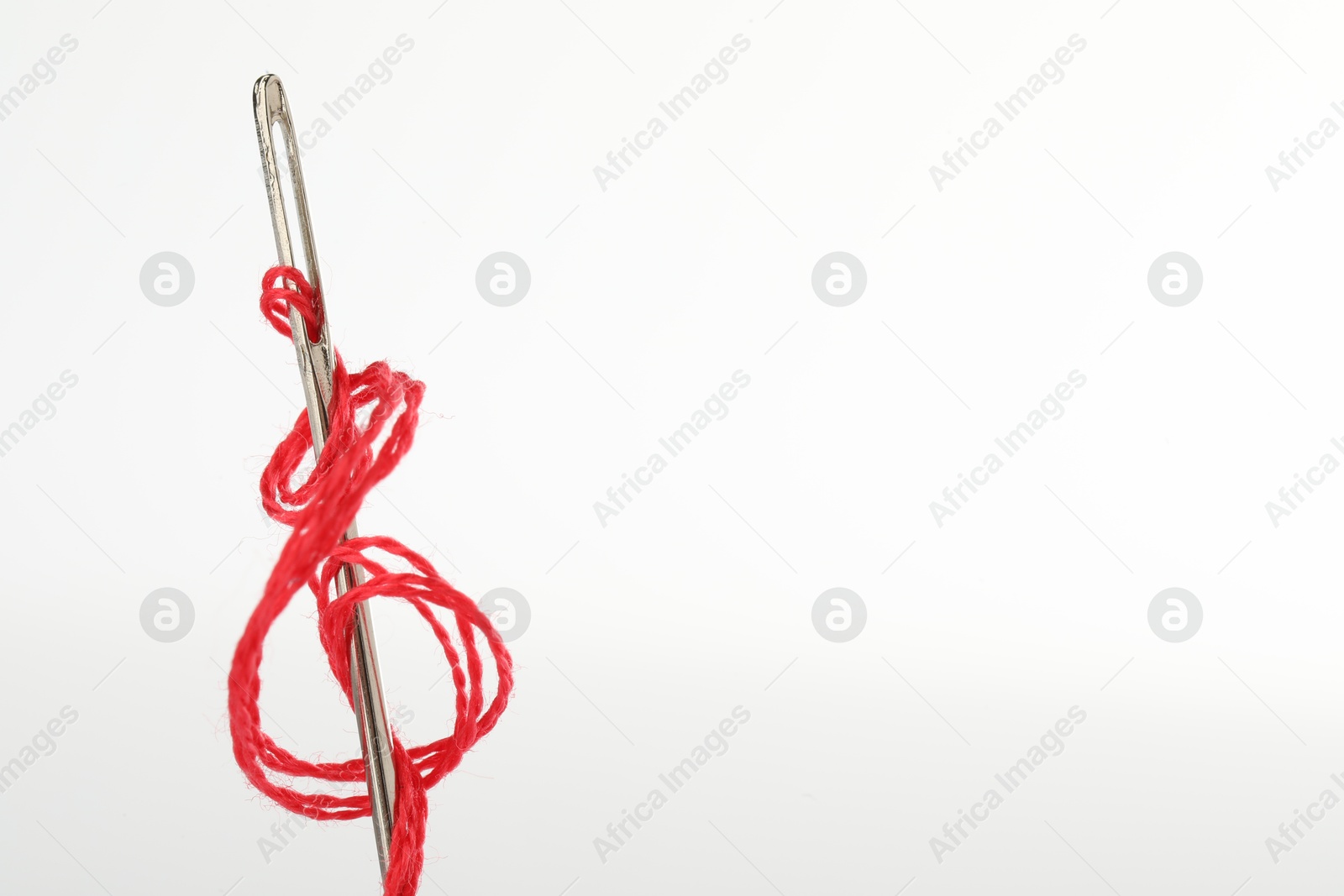 Photo of Sewing needle with red thread isolated on white, closeup