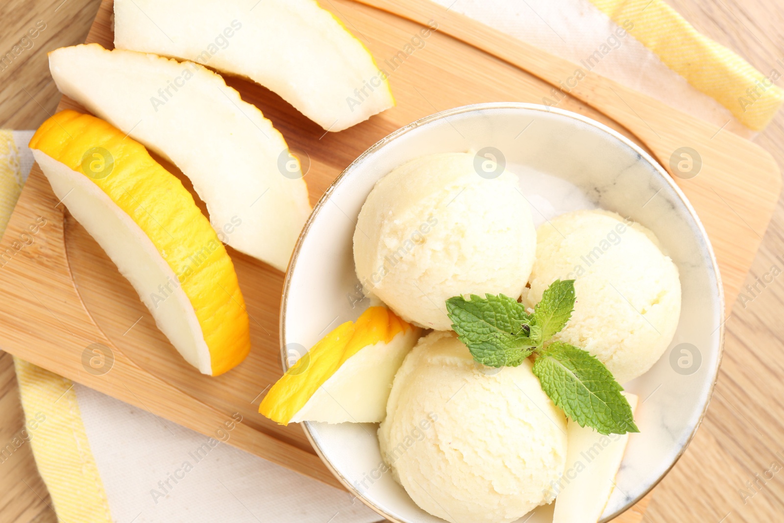 Photo of Scoops of tasty melon sorbet with mint in bowl and fresh fruit on wooden table, flat lay