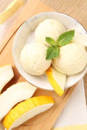 Scoops of tasty melon sorbet with mint in bowl and fresh fruit on wooden table, flat lay