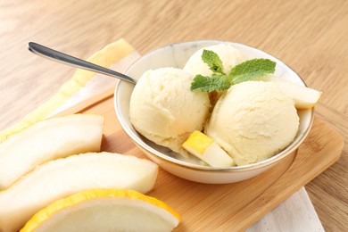 Photo of Scoops of tasty melon sorbet with mint in bowl and fresh fruit on wooden table, closeup