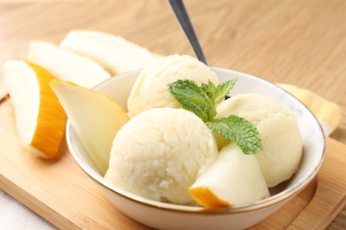 Scoops of tasty melon sorbet with fresh fruit and mint in bowl on table, closeup