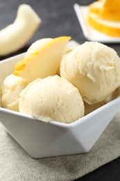 Photo of Scoops of tasty melon sorbet with fresh fruit in bowl on grey table, closeup