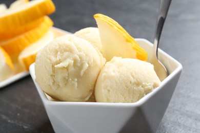 Scoops of tasty melon sorbet with fresh fruit and spoon in bowl on grey table, closeup