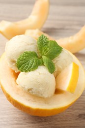 Scoops of tasty melon sorbet with mint in fresh fruit on wooden table, closeup