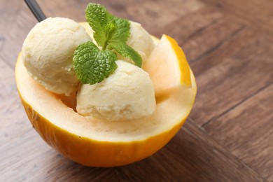 Scoops of tasty melon sorbet with mint in fresh fruit on wooden table, closeup