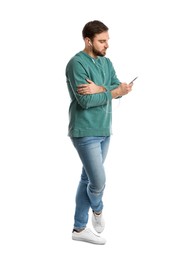 Photo of Young man in casual clothes with earphones and mobile phone listening to music on white background