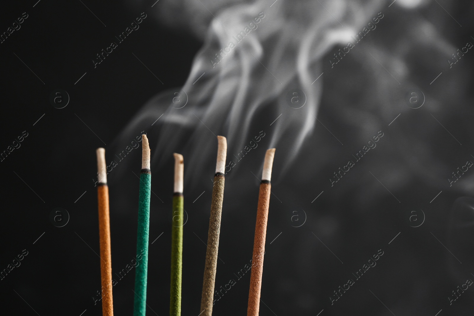 Photo of Aromatic incense sticks smoldering on black background