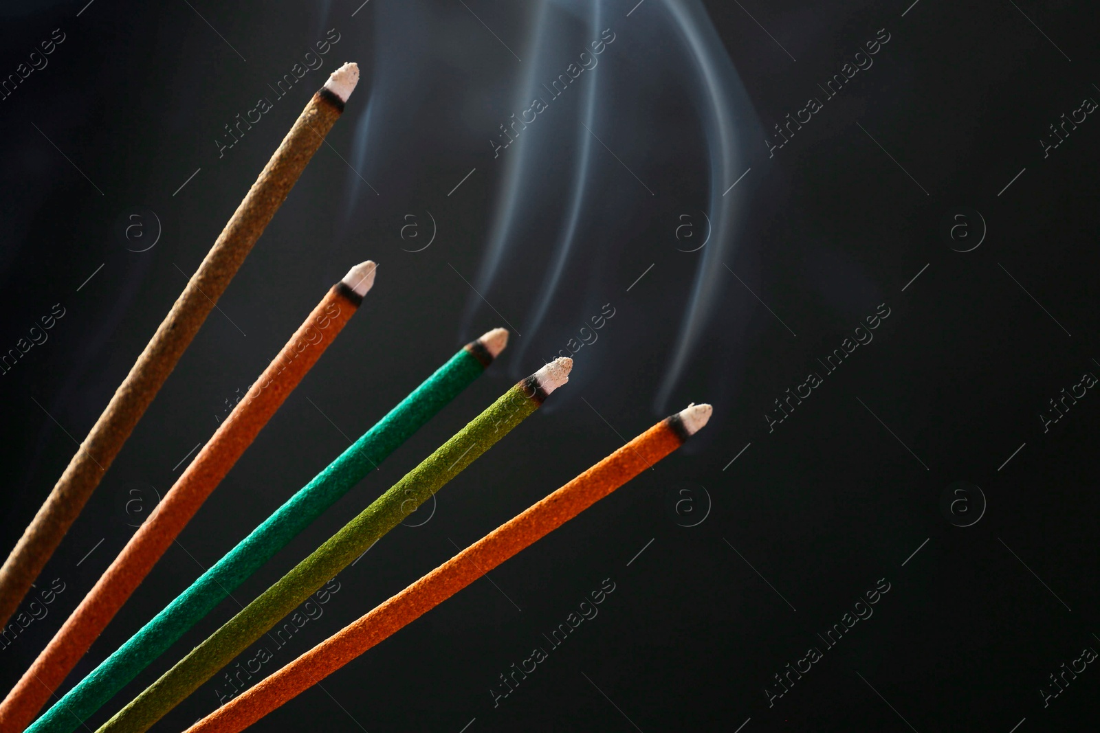 Photo of Aromatic incense sticks smoldering on black background