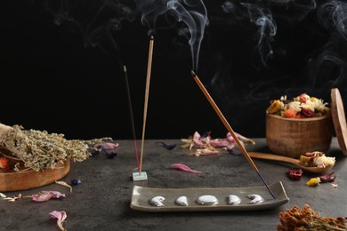 Photo of Aromatic incense sticks smoldering on grey table