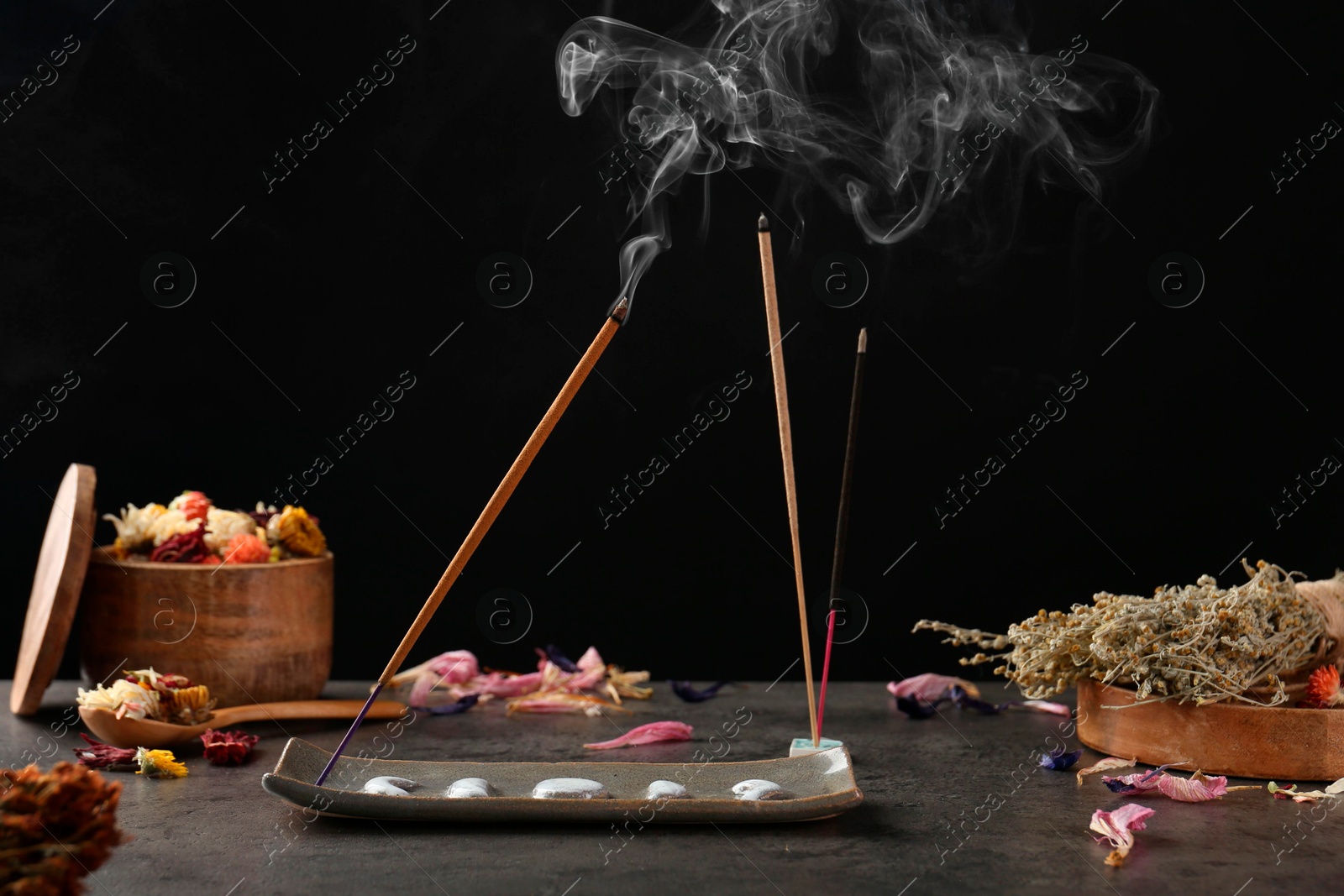 Photo of Aromatic incense sticks smoldering on grey table