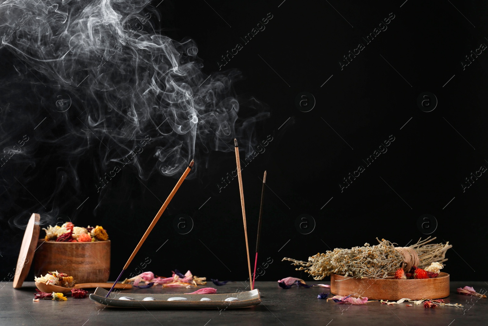 Photo of Aromatic incense sticks smoldering on grey table