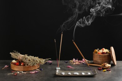 Photo of Aromatic incense sticks smoldering on grey table