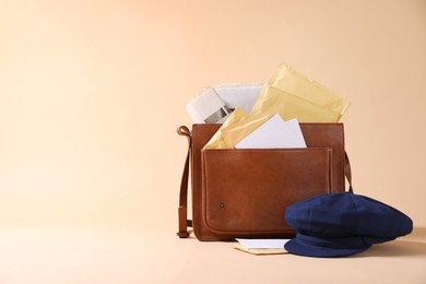 Brown postman's bag, envelopes, newspapers and hat on beige background. Space for text