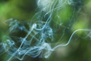 Photo of Smoke from incense stick on green blurred background