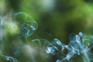 Smoke from incense stick on green blurred background