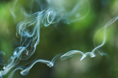 Photo of Smoke from incense stick on green blurred background