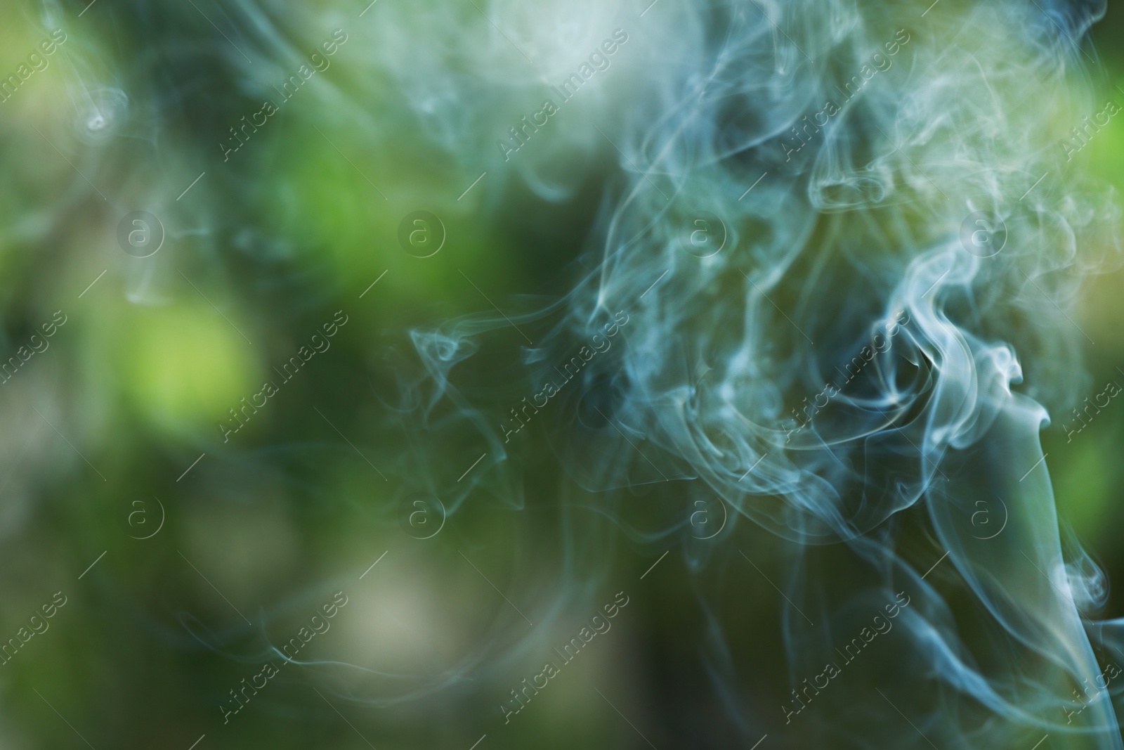 Photo of Smoke from incense stick on green blurred background