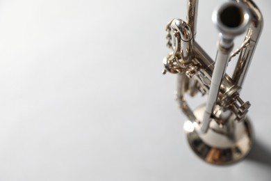 Photo of Closeup view of shiny trumpet on light grey background, space for text. Wind musical instrument