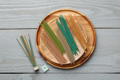 Incense sticks and small ceramic stand on gray wooden table, flat lay