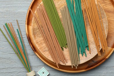 Incense sticks and small ceramic stand on gray wooden table, flat lay