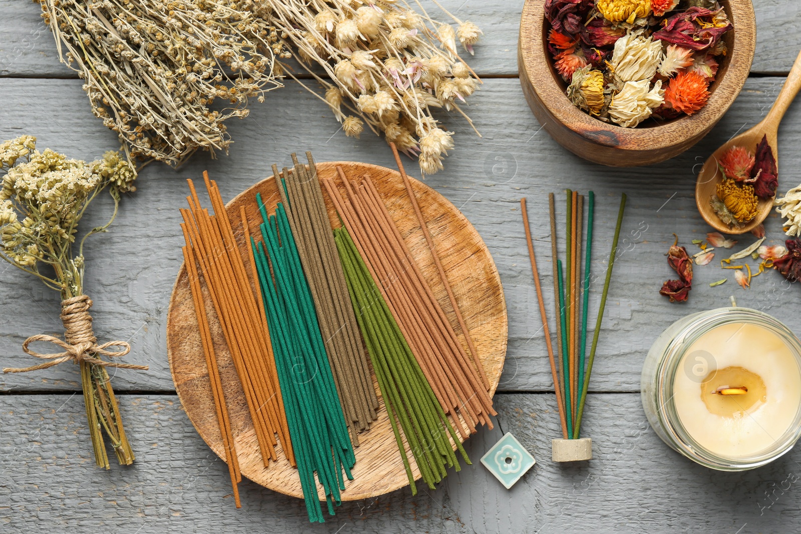 Photo of Incense sticks, dry flowers and candle on gray wooden table, flat lay