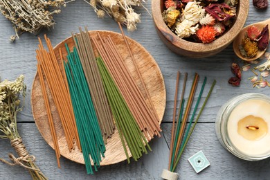 Photo of Incense sticks, dry flowers and candle on gray wooden table, flat lay