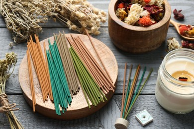 Incense sticks, dry flowers and candle on gray wooden table