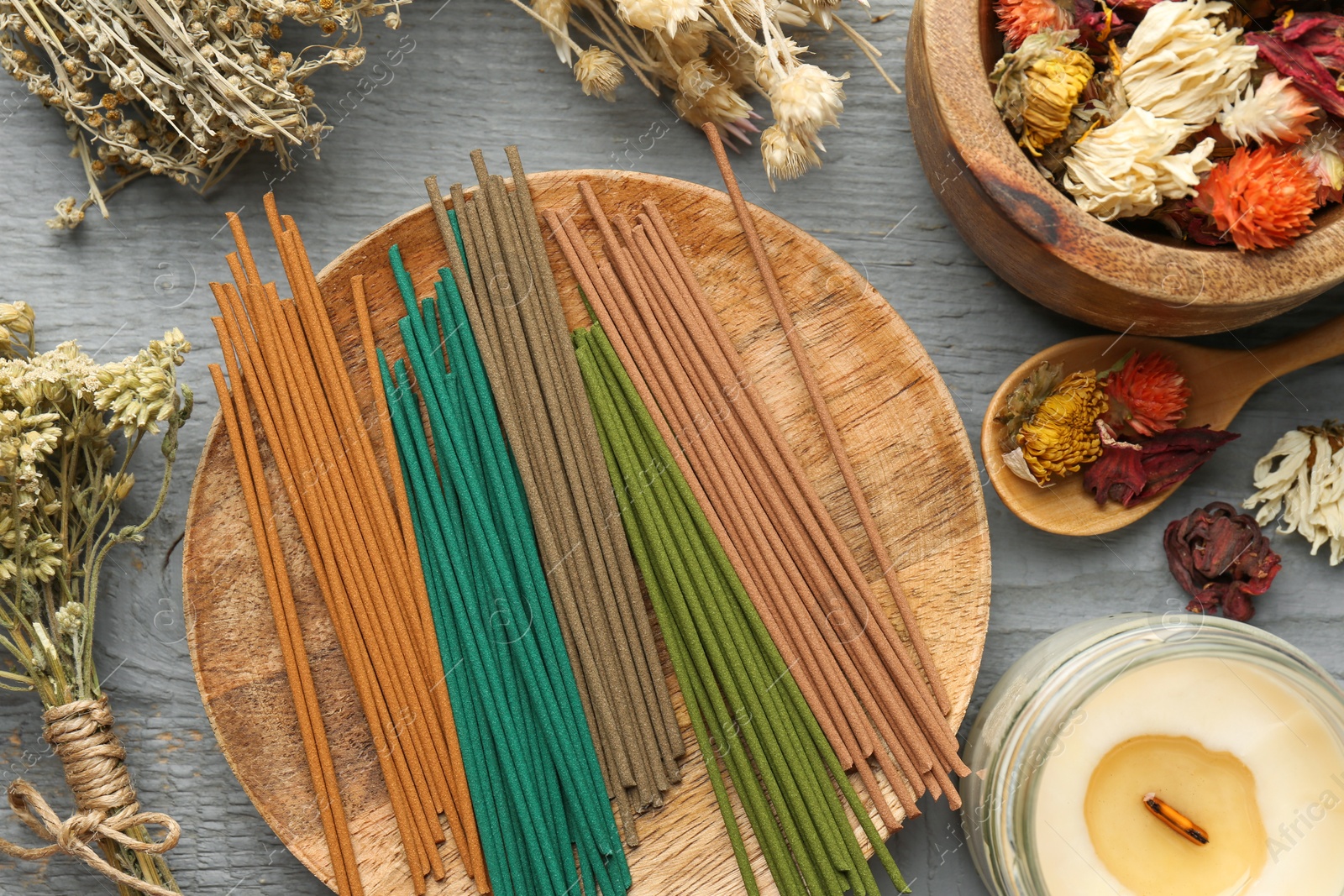 Photo of Incense sticks, dry flowers and candle on gray wooden table, flat lay