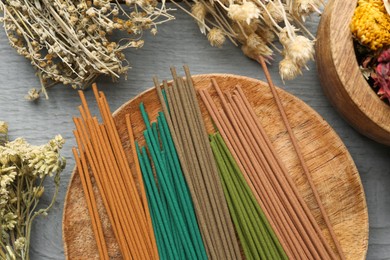 Incense sticks and dry flowers on gray wooden table, flat lay