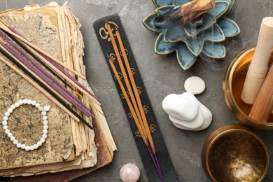 Flat lay composition with incense sticks on gray textured table. Om ligature