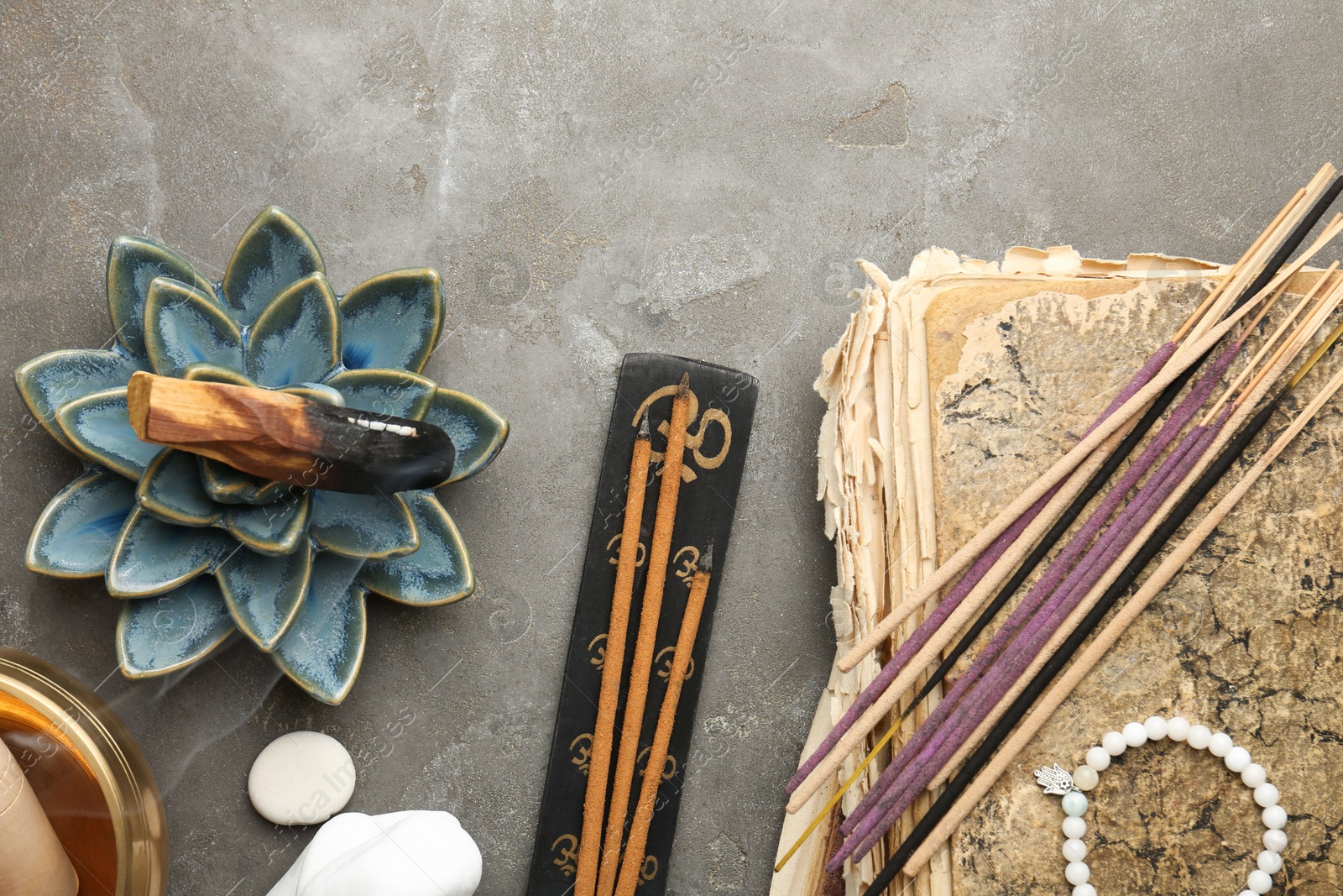 Photo of Flat lay composition with incense sticks on gray textured table. Om ligature