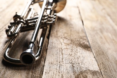 One trumpet on wooden table, closeup. Space for text