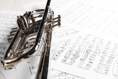 Trumpet on music sheet papers with notes, closeup. Space for text