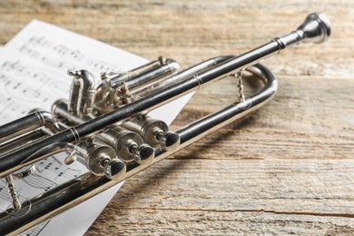 Trumpet and music sheets on wooden table, closeup