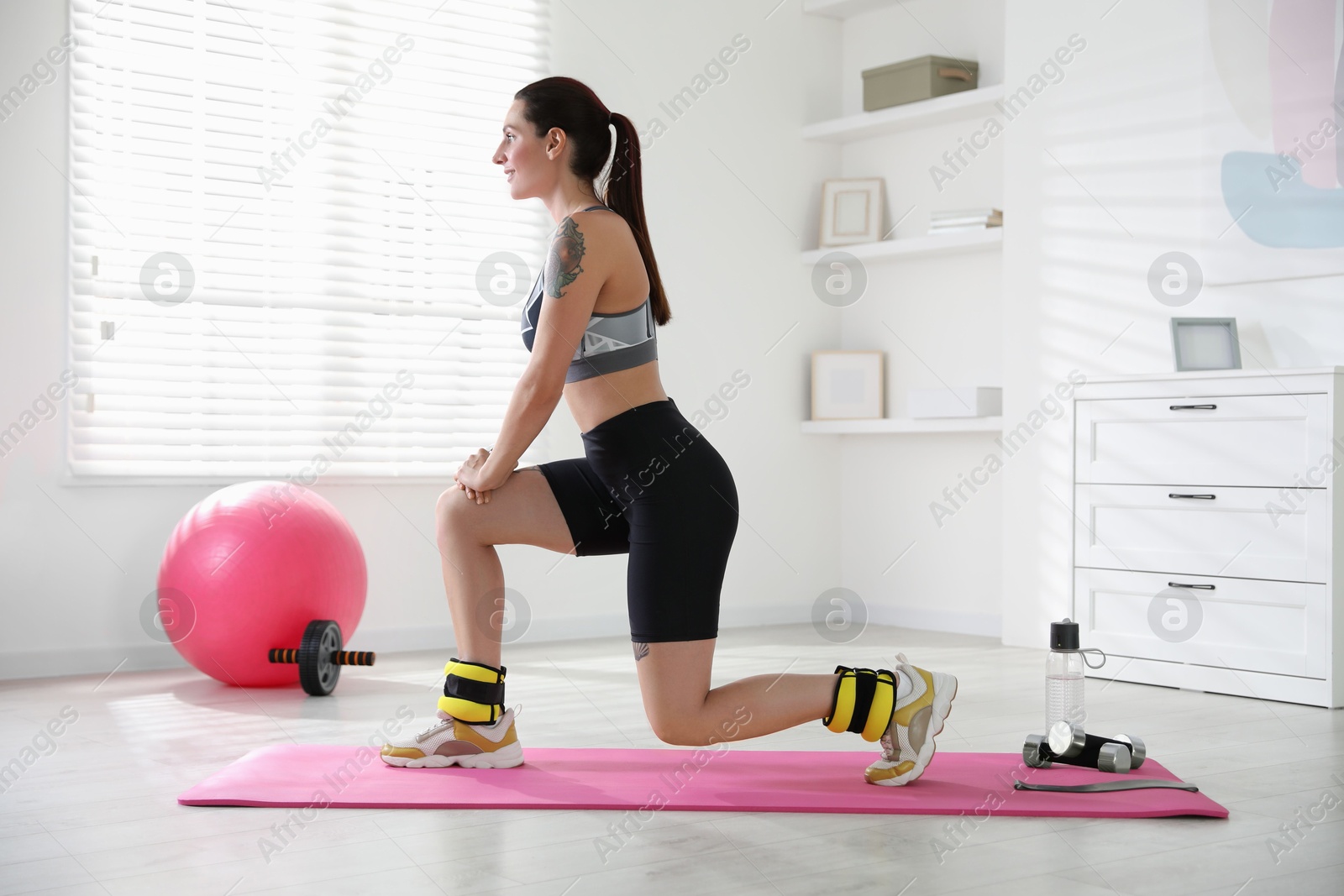 Photo of Beautiful woman with ankle weights doing exercises indoors