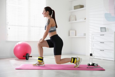 Beautiful woman with ankle weights doing exercises indoors