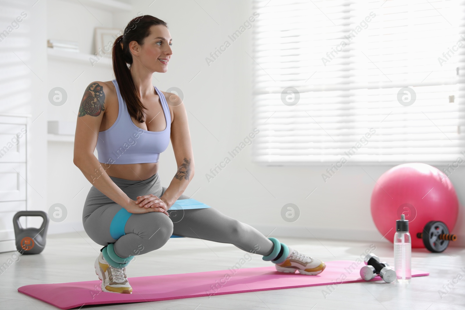 Photo of Woman with ankle weights and elastic band training indoors