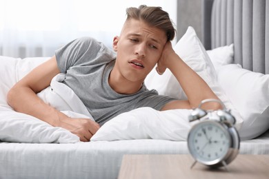 Photo of Sleepy young man waking up in bedroom at lunch time