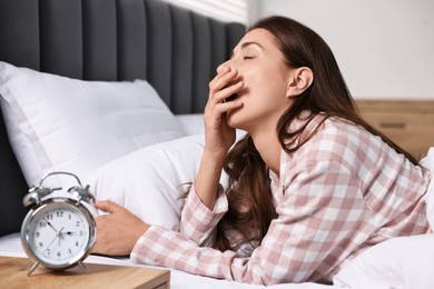 Sleepy woman waking up in bedroom at lunch time