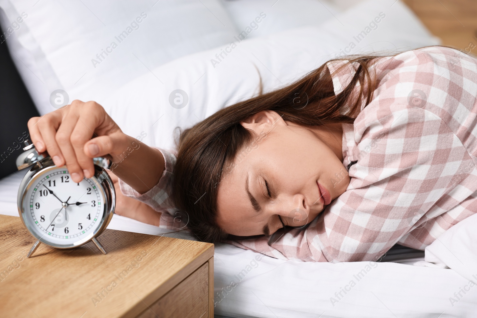 Photo of Sleepy woman turning off alarm clock in bedroom at lunch time