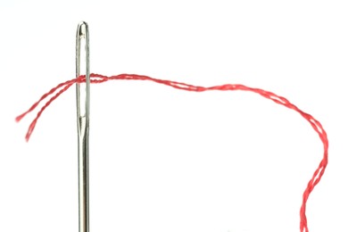 Photo of Sewing needle with red thread on white background, closeup