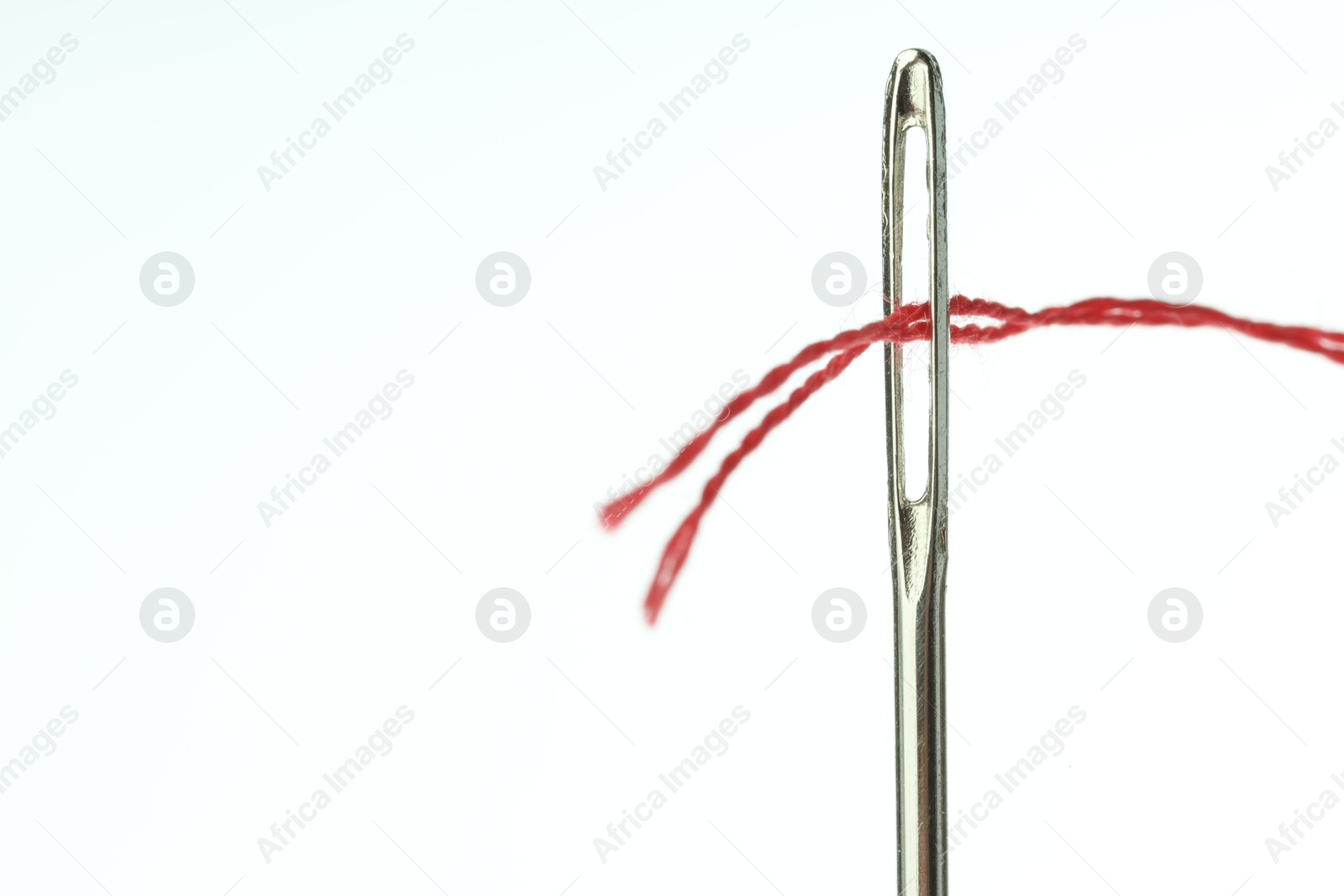 Photo of Sewing needle with red thread on white background, closeup