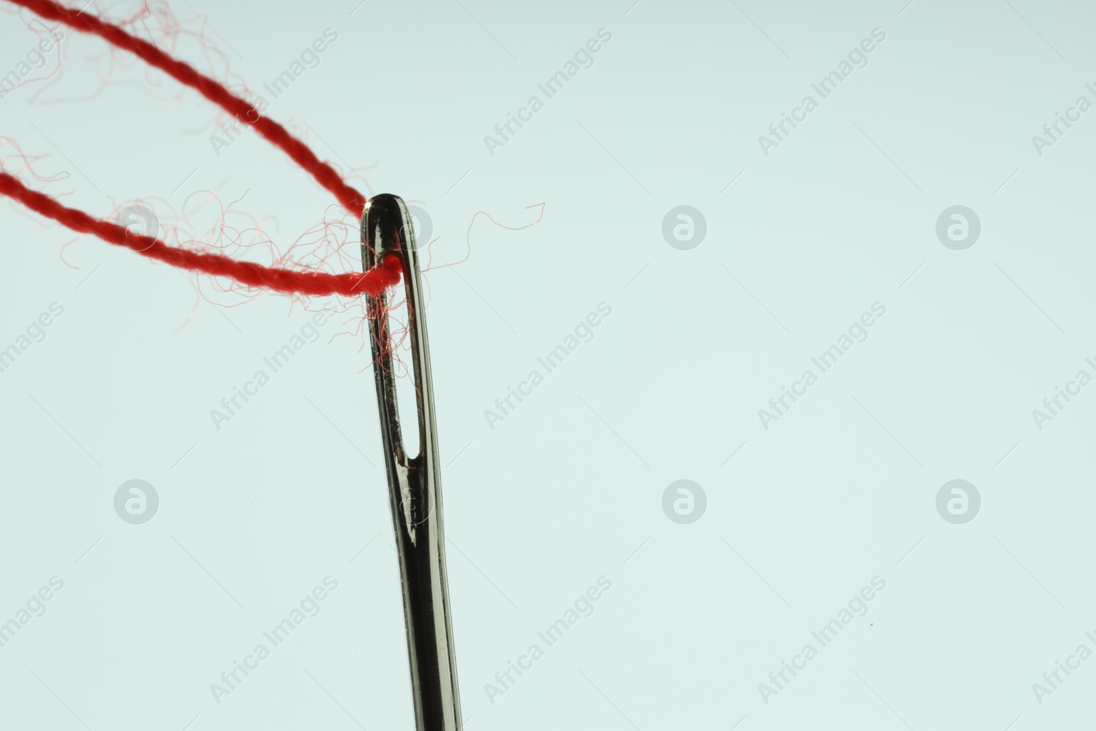 Photo of Sewing needle with red thread on white background