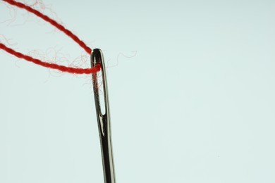 Photo of Sewing needle with red thread on white background