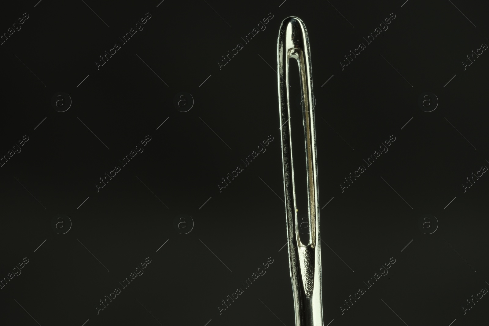 Photo of Sewing needle on black background, closeup view. Space for text